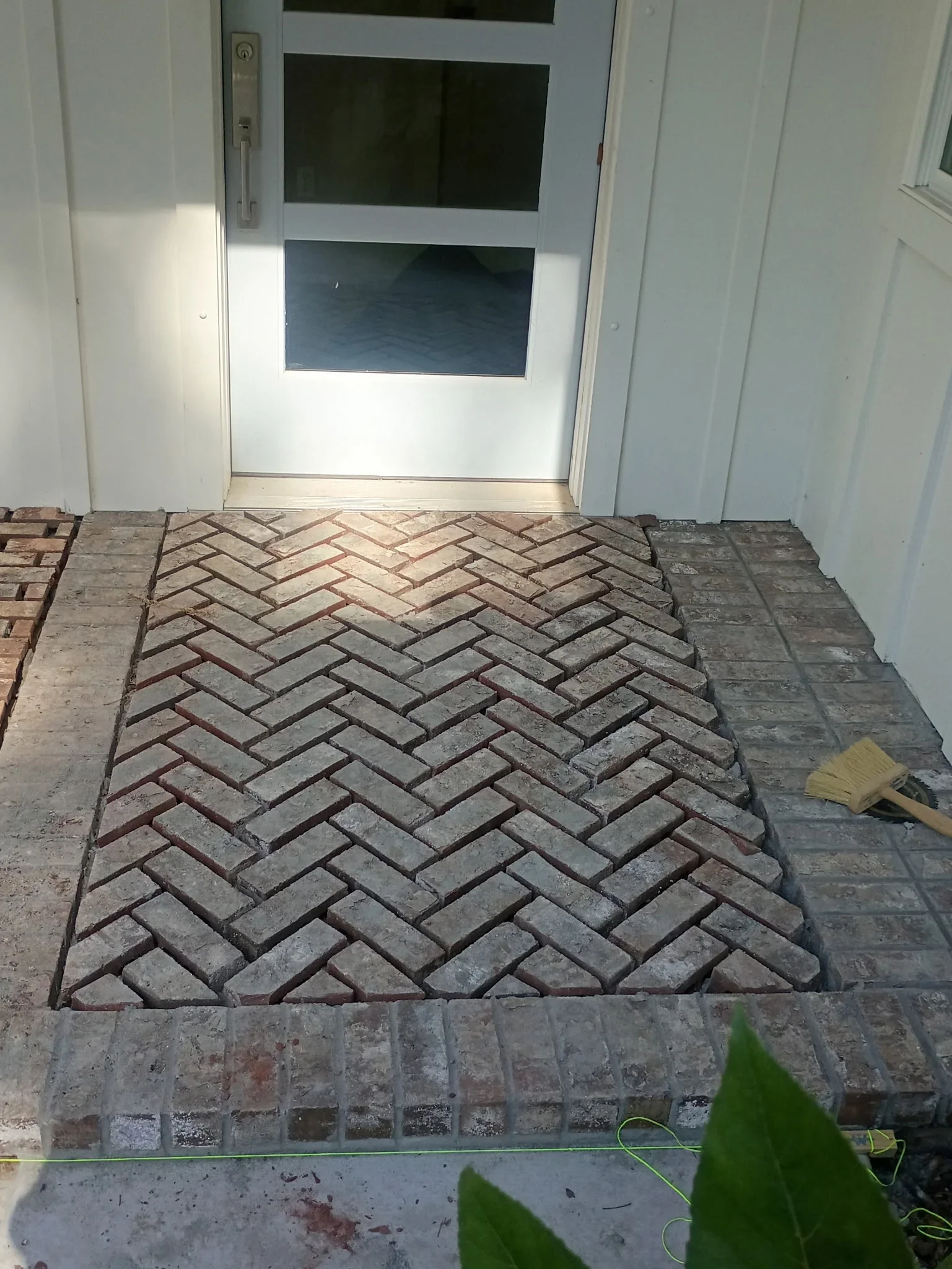 Herringbone pattern clay brick entryway with clean grout lines and border transitions