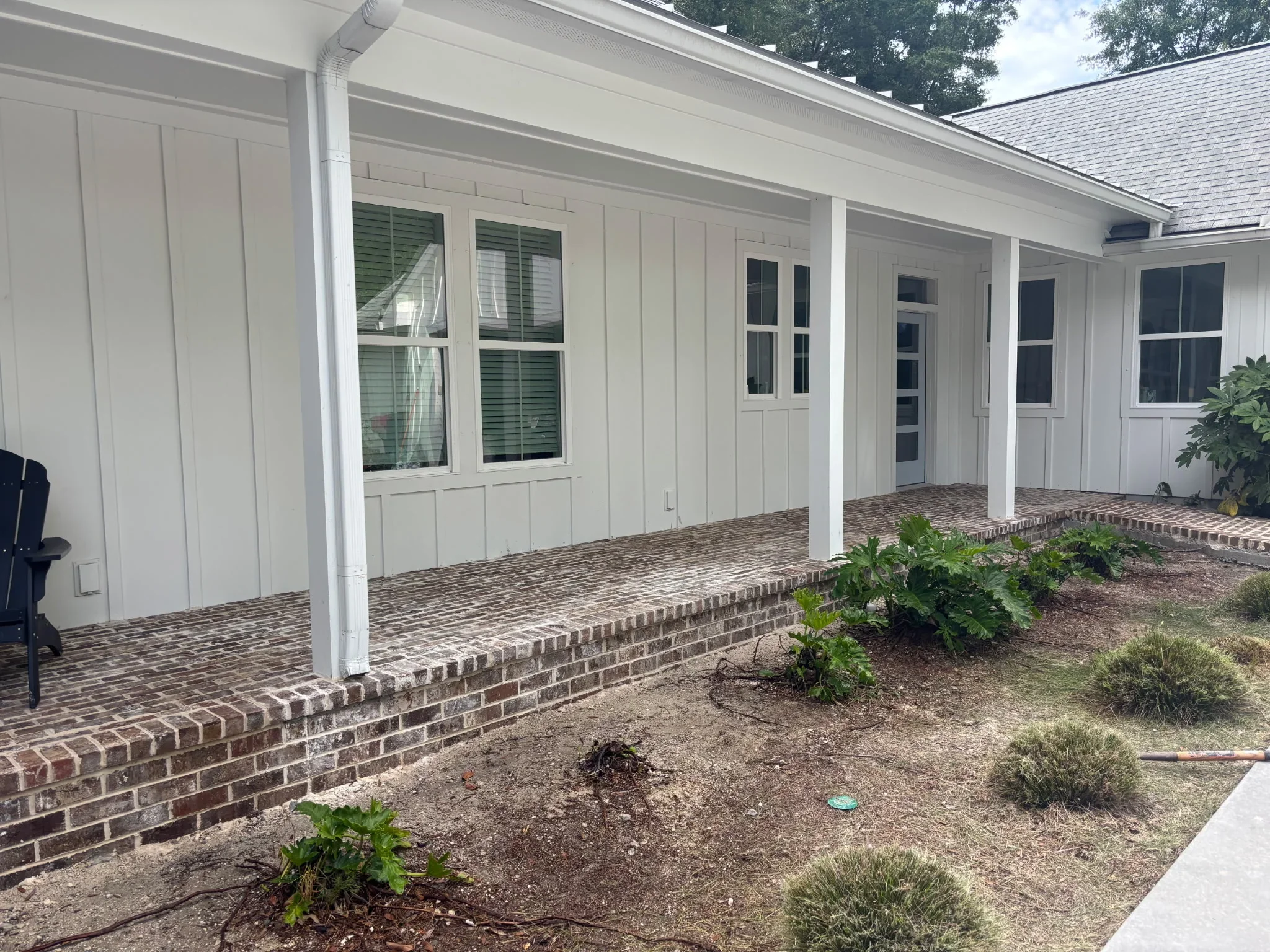 Brick paver patio with concrete base, white columns, and landscaping beds