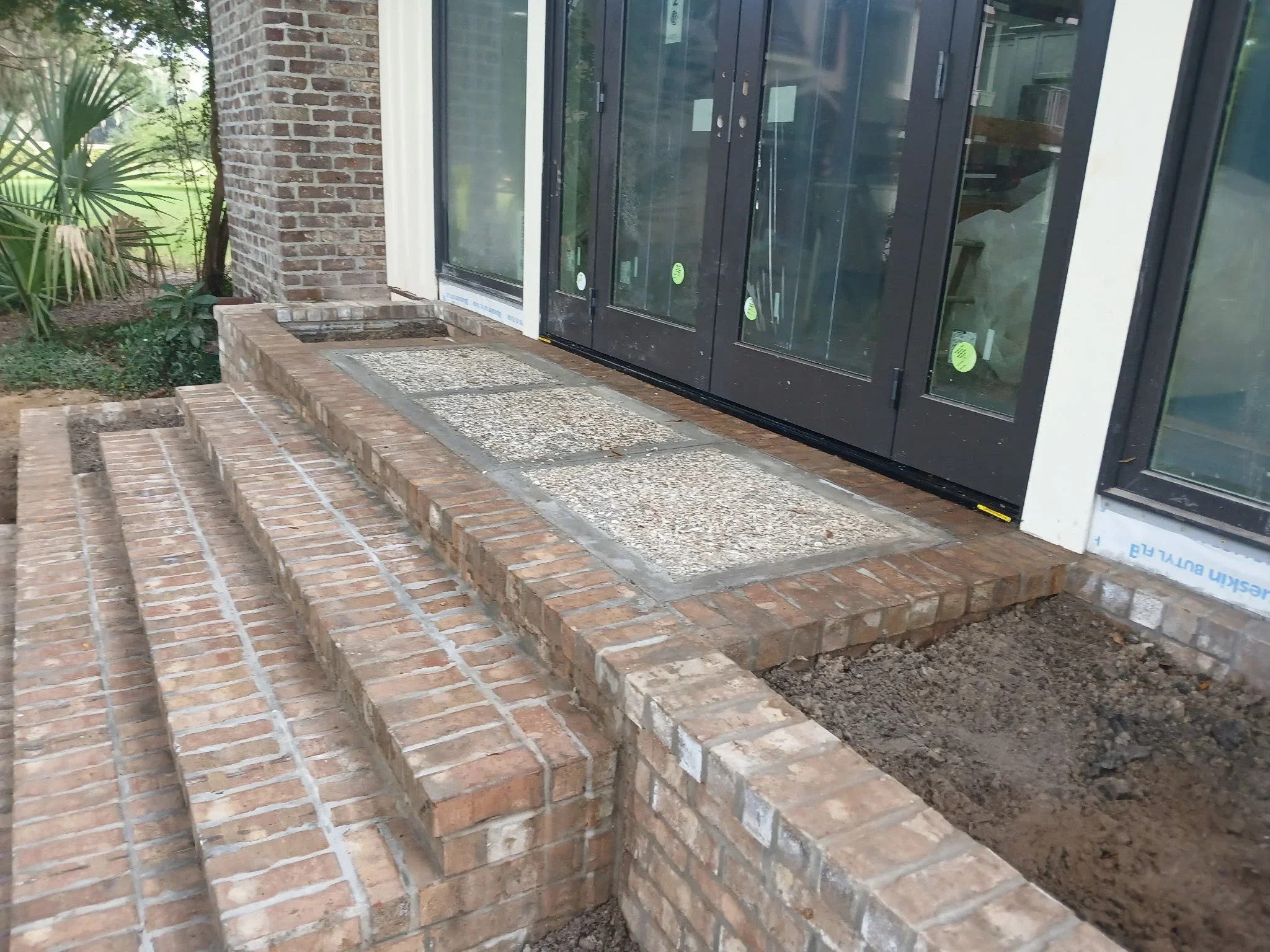 Brick paver patio with gravel inlay strips and raised borders leading to glass doors