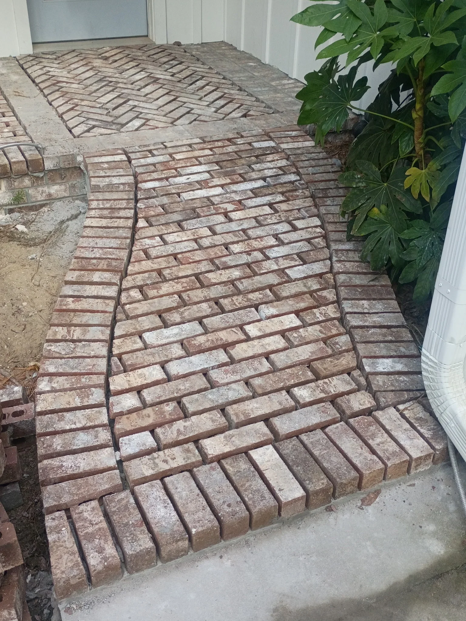 Herringbone pattern clay brick entryway with concrete base and grout joints