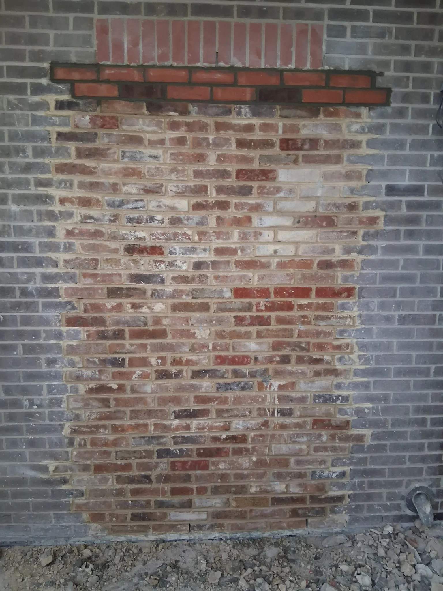 Brick wall with rectangular opening showing removed brick infill and exposed masonry structure