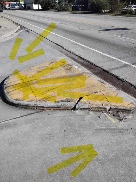 Removed concrete section with yellow utility markings on street surface
