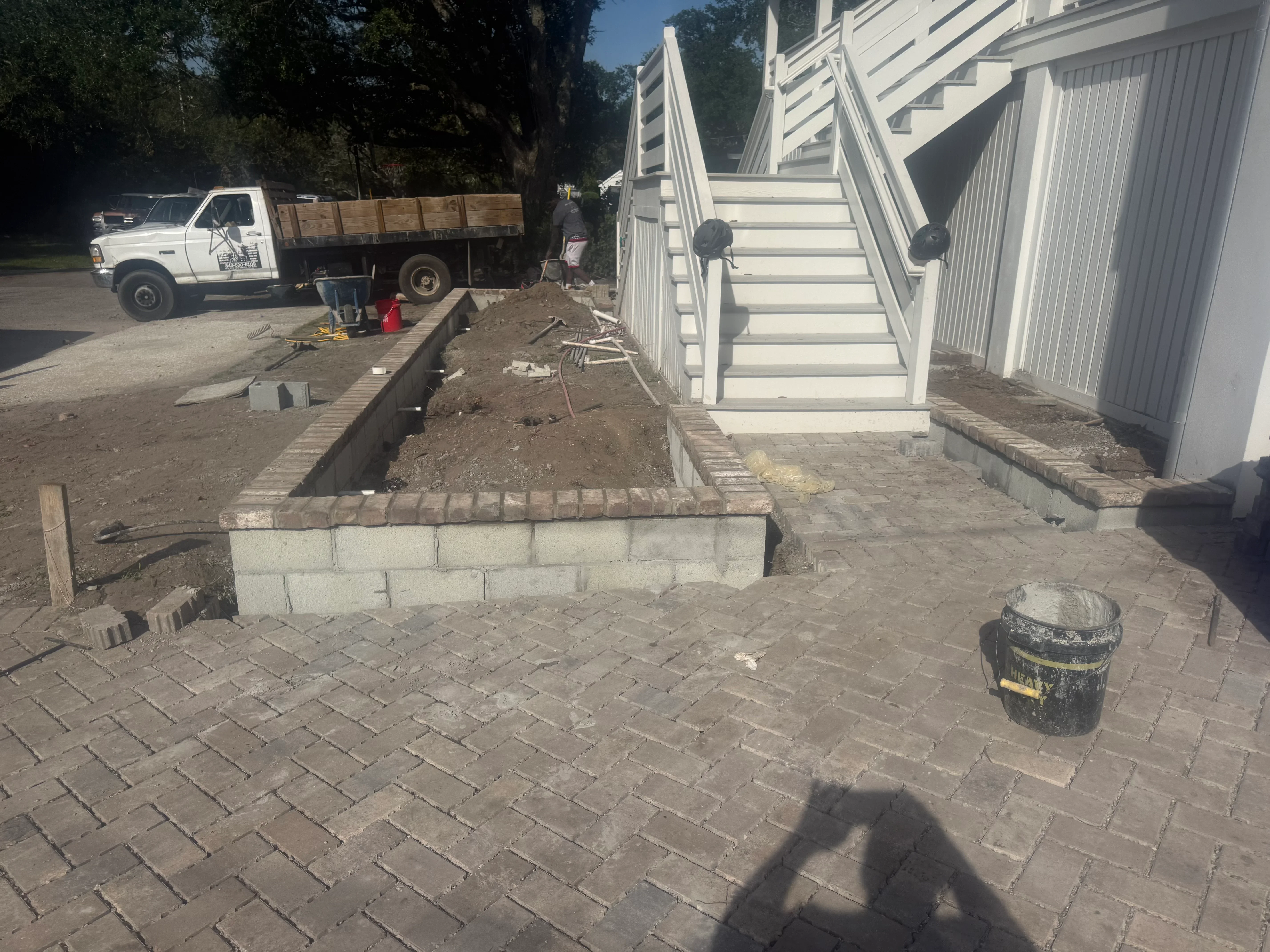 Concrete paver patio with herringbone pattern and concrete block retaining wall during installation