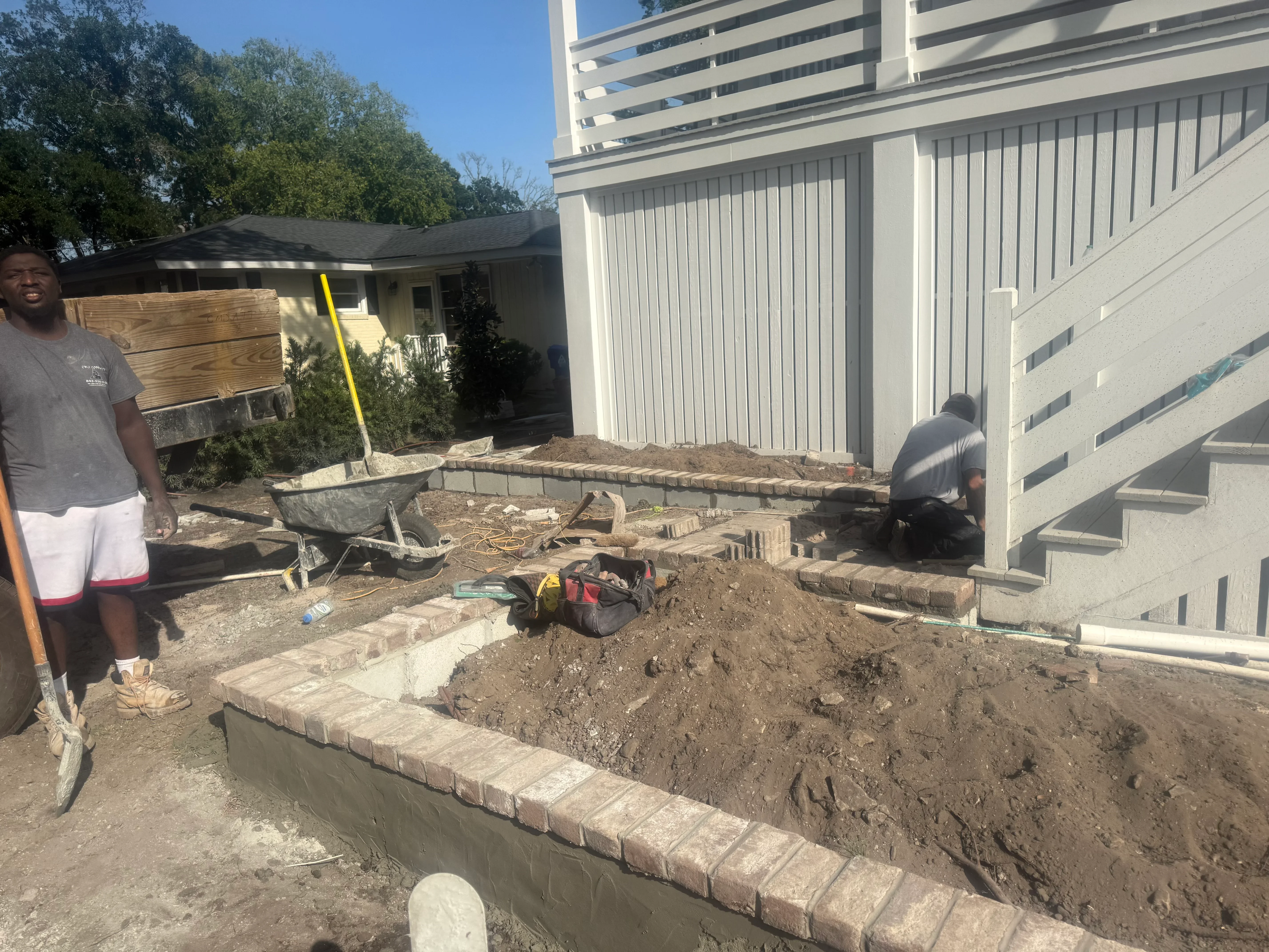 Concrete block retaining wall installation with excavated soil and landscape grading in residential backyard