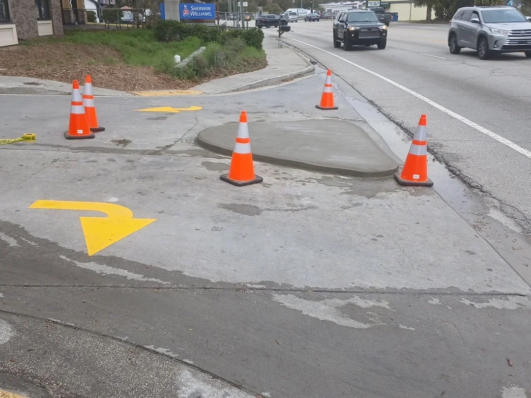 Concrete parking lot repair with patched sections and safety cones marking work area