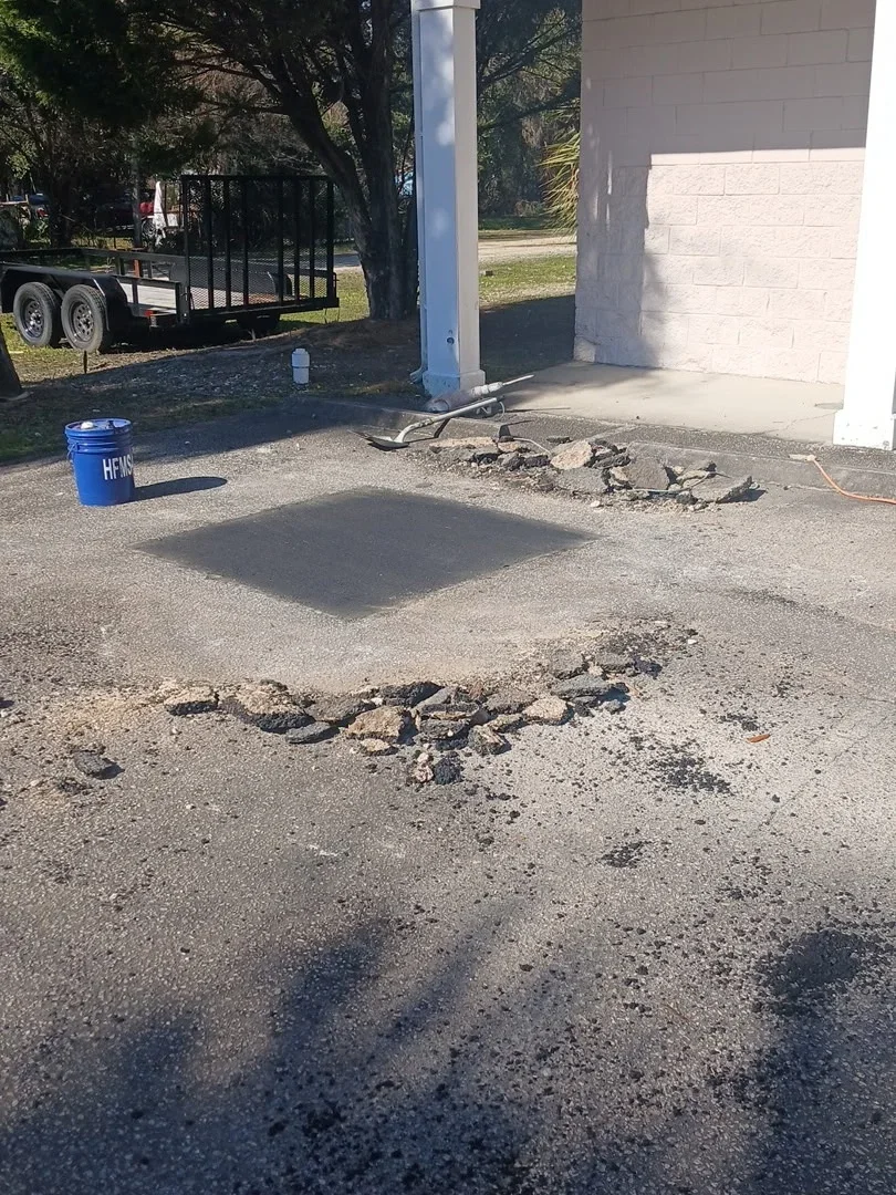 Concrete driveway patch repair with fresh material applied to damaged asphalt section