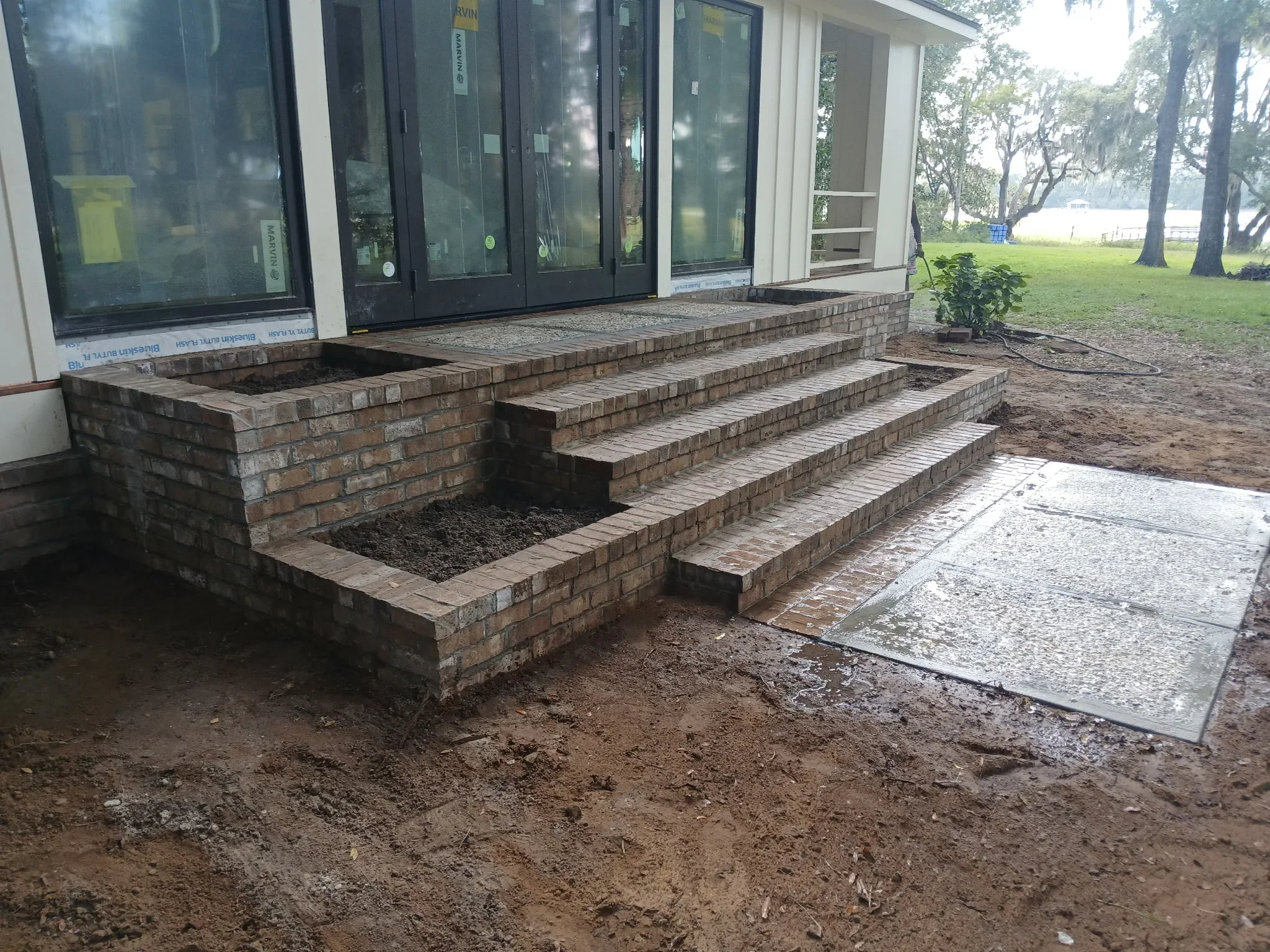 Stacked brick planter box and tiered entry steps with brick veneer construction