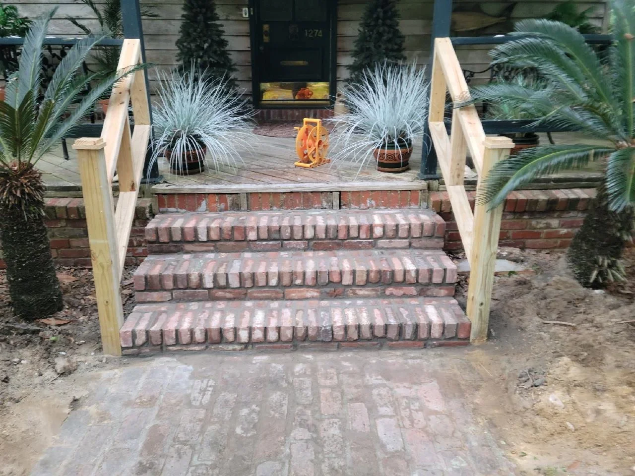 Brick entry steps with wood railings and concrete landing pad