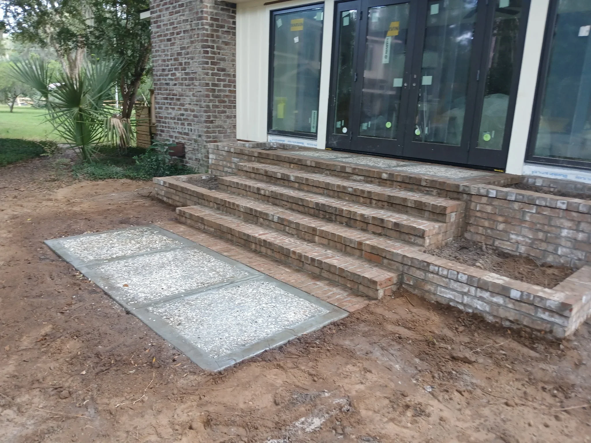 Brick retaining wall with concrete aggregate pad at residential entry