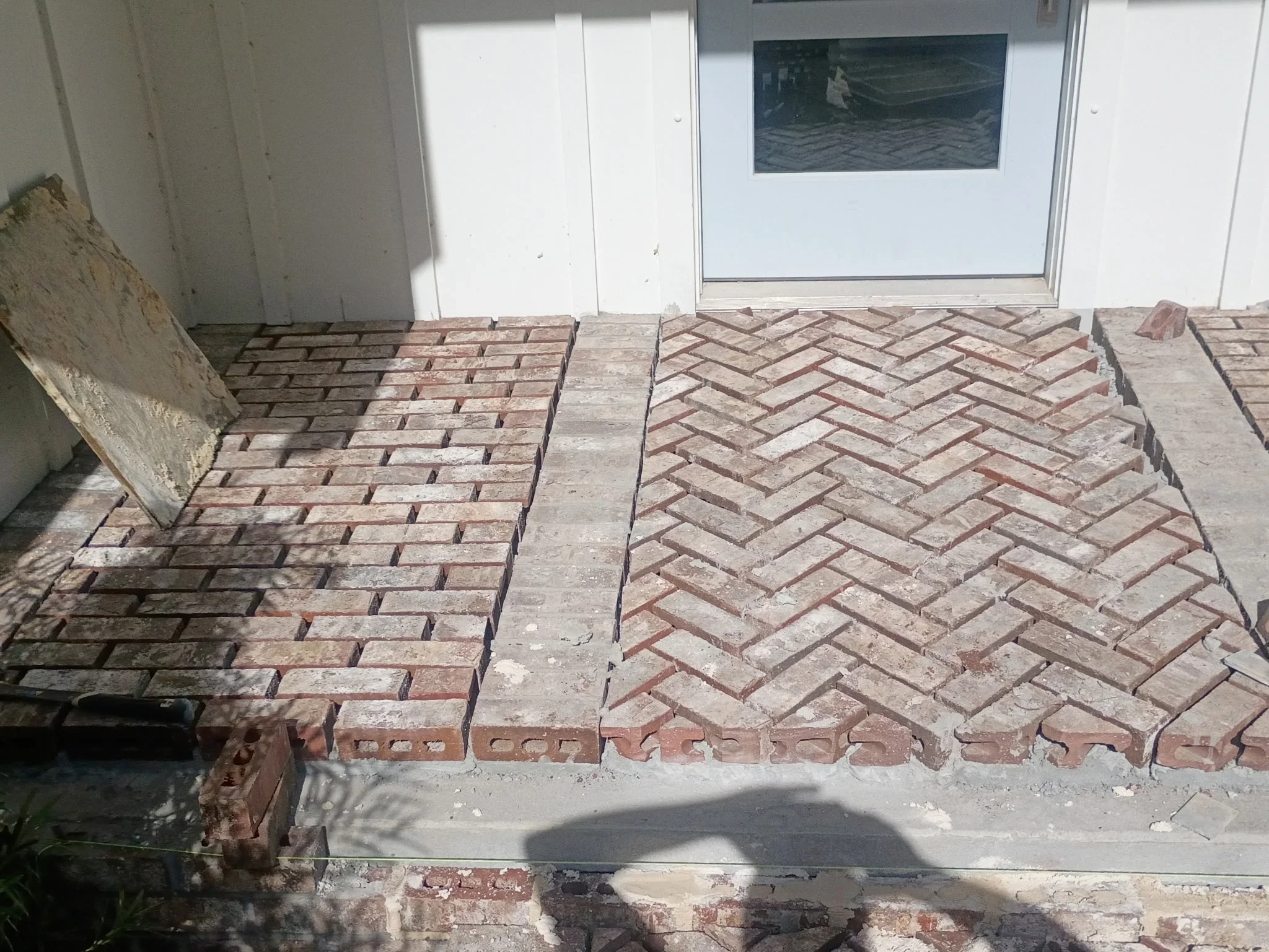 Herringbone pattern brick patio with two-section layout and mortar joints